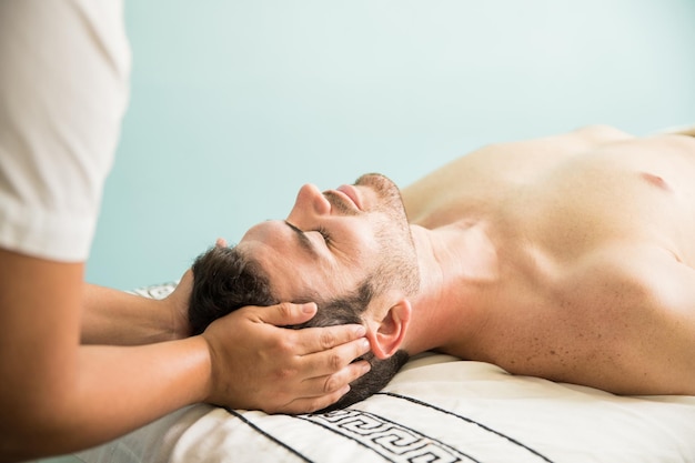 Profile view of a good looking young man looking very relaxed while getting pampered at a spa