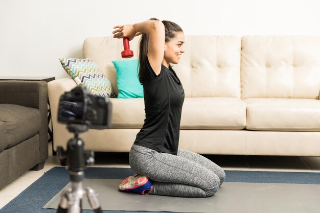 Profile view of a young woman in sporty outfit recording a video for her fitness blog