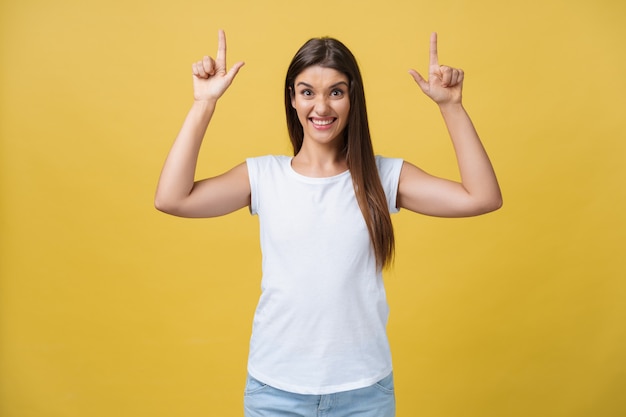 Profile of a woman pointing on copy space for an advertisement isolated on a yellow background.