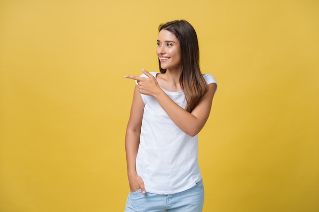 Profile of a woman pointing on copy space for an advertisement isolated on a yellow background.