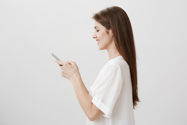 Профиль молодой красивой женщины текстовых сообщений, используя мобильный телефон, заказать онлайн