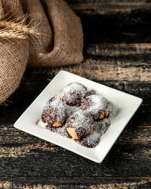 Foto gratuita profitrole con sciroppo di cioccolato e scaglie di cocco sul piatto