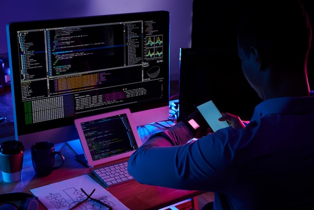 Programmer scanning screen on his smartwatch with smartphone camera