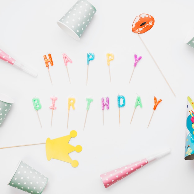 Free photo prop; party horn and party hat around the happy birthday candles against white background