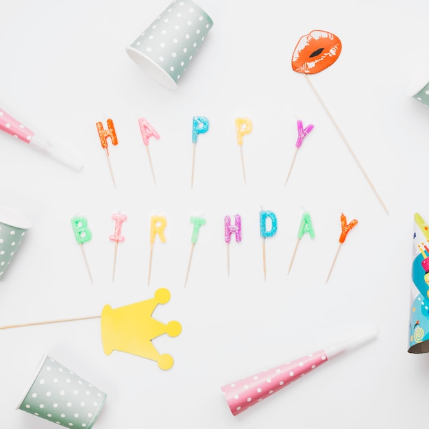 Prop; party horn and party hat around the happy birthday candles against white background