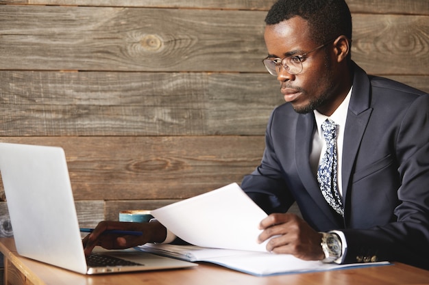 Free photo prosperous top-manager in formal suit working with papers using laptop