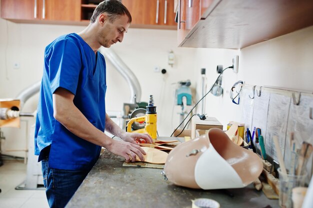 Prosthetist man making orthopedic insoles while working in laboratory