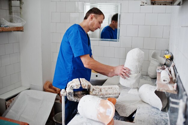 Prosthetist man making prosthetic leg while working in laboratory makes a model of plaster