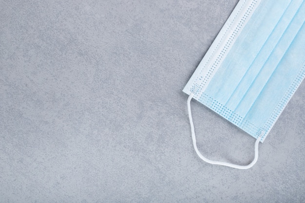 A protective medical face mask on a gray surface