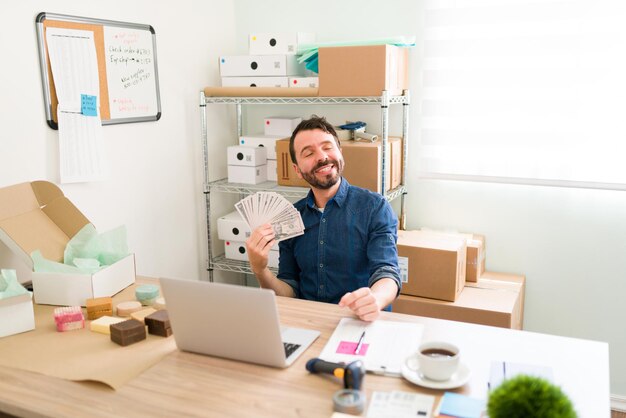 Proud business owner earning a lot of money with his new startup and e-commerce. Hispanic man holding a lot of cash because of many customer orders