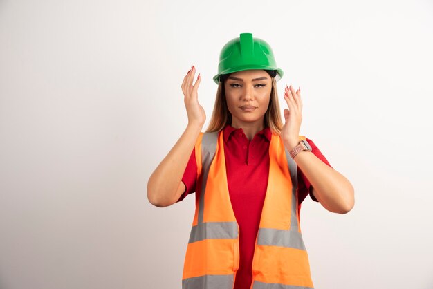 Proud female worker posing with green helmet on white background.
