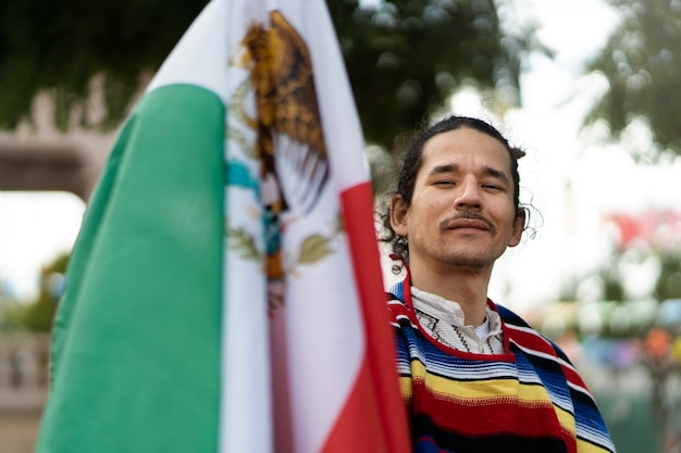 Proud man holding mexican flag medium shot