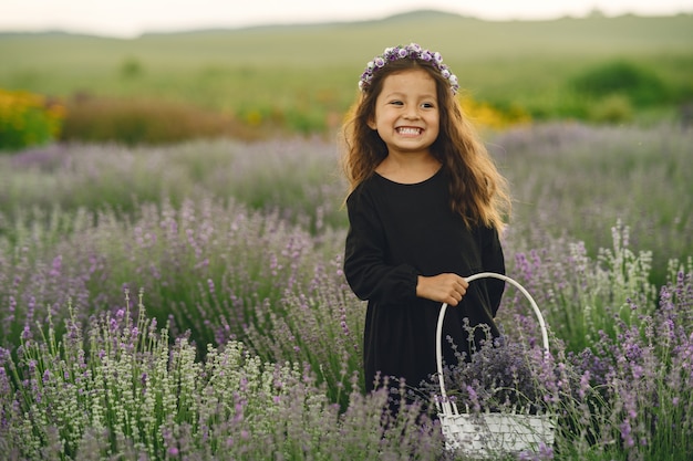 Provence child relaxing in lavender field. Little lady in a black dress. Girl with bag.