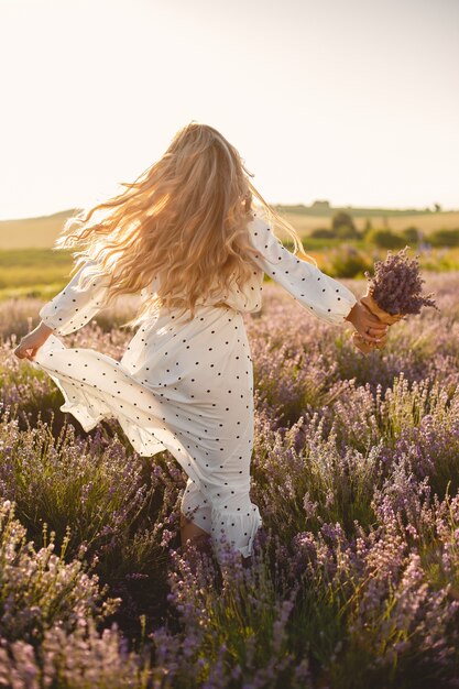 Provence woman relaxing in lavender field. Lady in a white dress. Girl with bouquete of flowers.