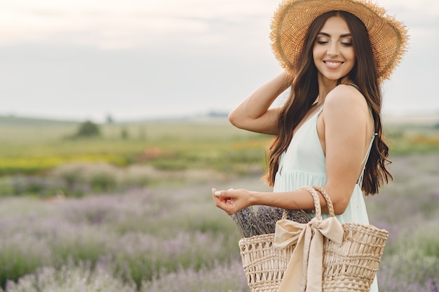 Foto gratuita provenza donna rilassante nel campo di lavanda. dama con un cappello di paglia. ragazza con borsa.