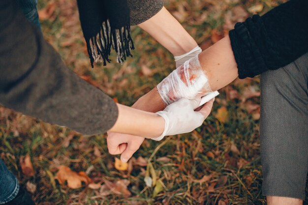 Providing first aid in the park. Man bandaged  injured arm. Guy helps a friend.