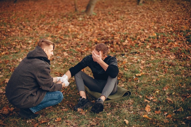 Free photo providing first aid in the park. man bandaged  injured arm. guy helps a friend.