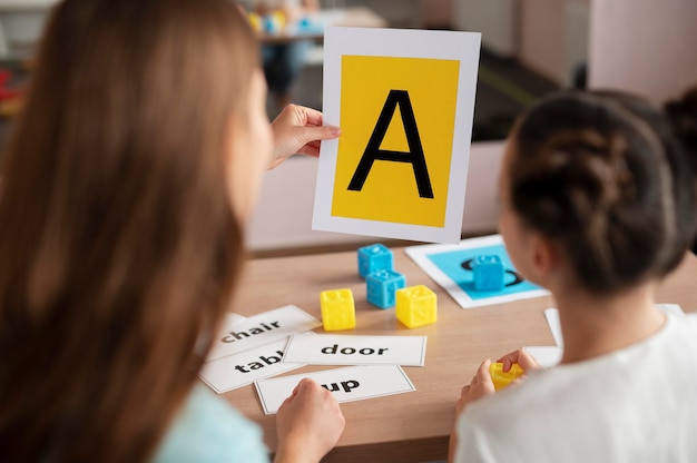 Foto gratuita psicologo che aiuta una bambina nella logopedia al chiuso