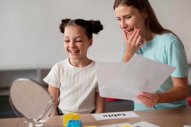 Foto gratuita psicologo che aiuta una bambina nella logopedia al chiuso