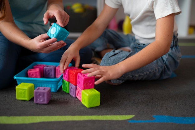 Psychologist helping a little girl in speech therapy indoors