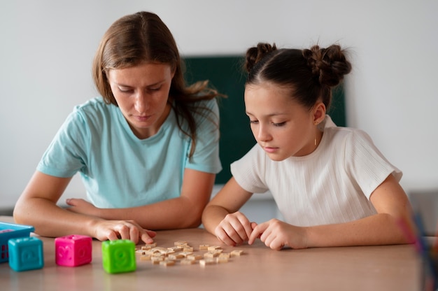 Psychologist helping a little girl in speech therapy indoors