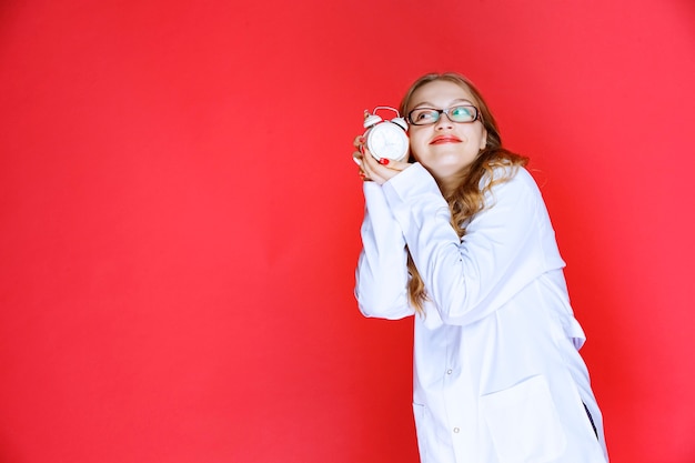 Psychologist holding an alarm clock pointing to the right sleep time.