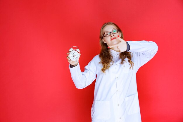 Psychologist holding an alarm clock pointing to the right sleep time.