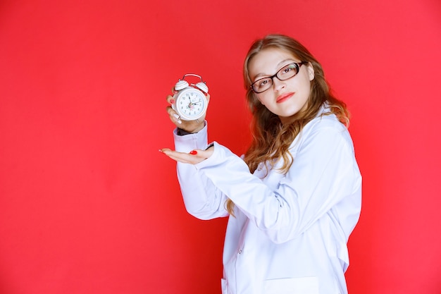 Psychologist holding an alarm clock pointing to the right sleep time.