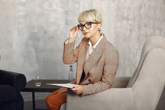 Psychologist with glasses sitting on a chair at the office