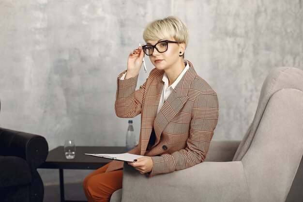 Psychologist with glasses sitting on a chair at the office