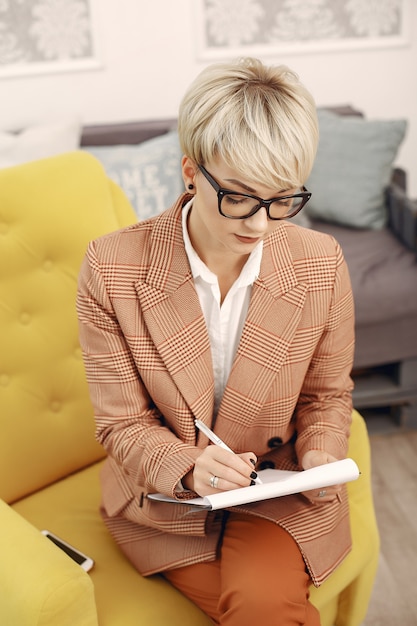 Psychologist with glasses sitting on a chair at the office