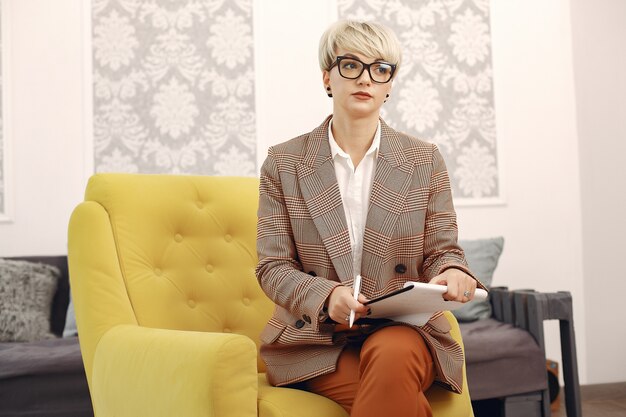 Psychologist with glasses sitting on a chair at the office