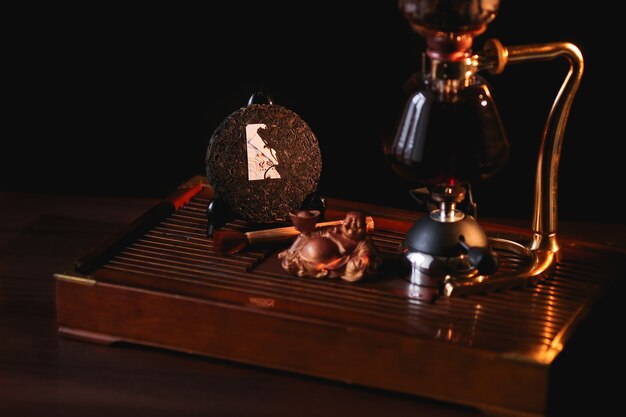 Puer tea in the siphon with extruded pancake Shu Puer and Buddha statue 