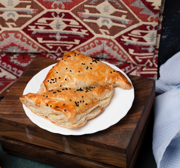 Puff pastry snacks in a white plate on a wooden board