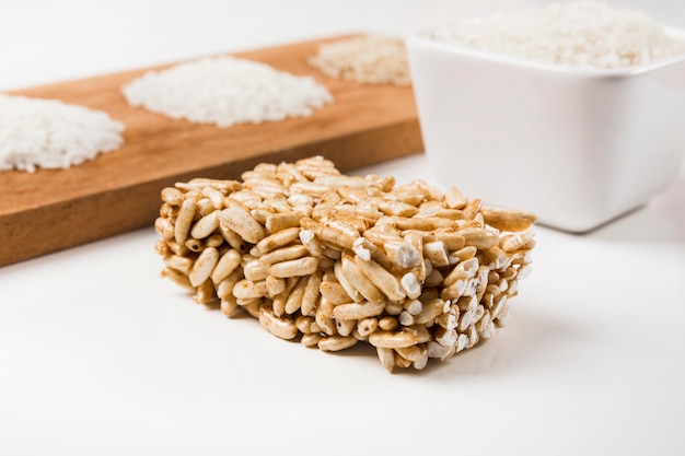 Puffed rice bar with uncooked white rice on white backdrop