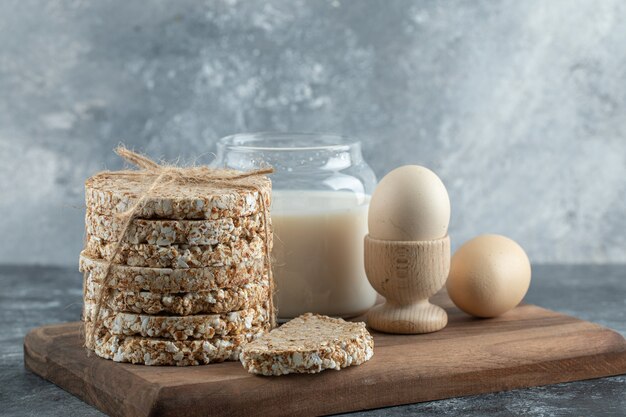 Puffed rice cakes, milk and eggs on wooden board