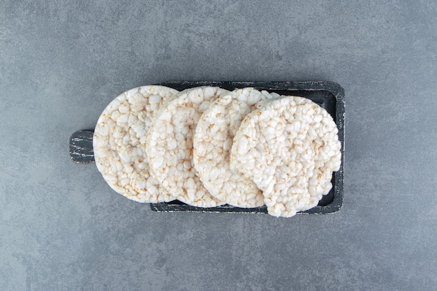 Puffed rice cakes on a wooden dark board.