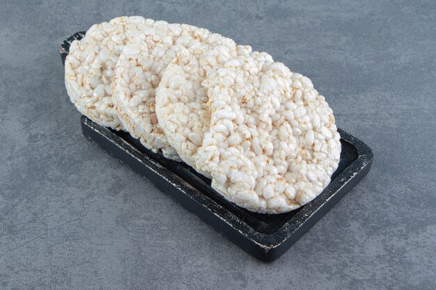 Puffed rice cakes on a wooden dark board.