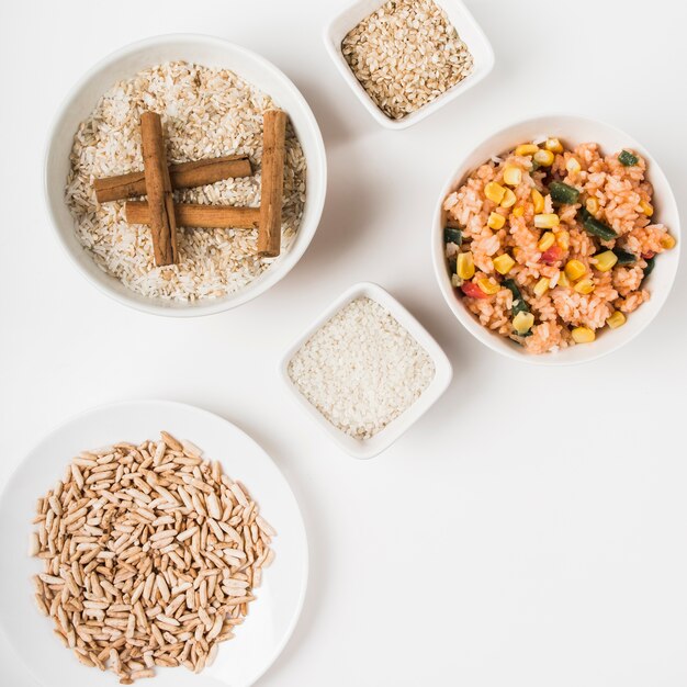 Puffed rice; chinese fried rice and uncooked rice with cinnamon sticks on white backdrop