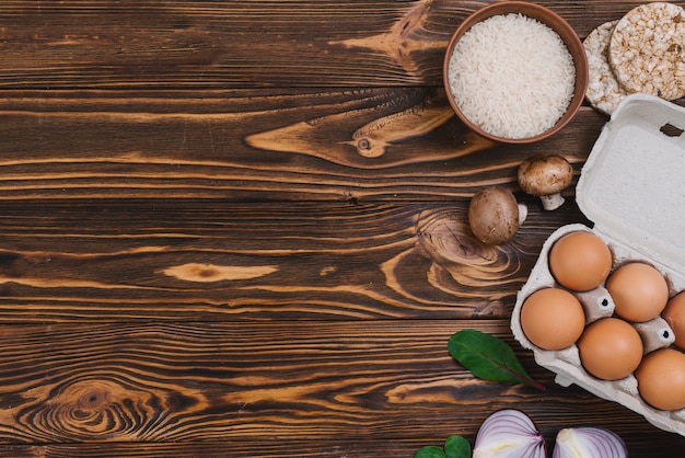 Puffed rice; rice grains; mushroom; eggs and onion over wooden desk