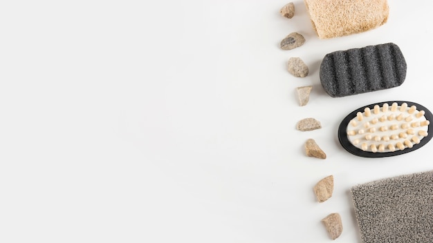 Free photo pumice stone; massage brush; loofah and spa stones arranged in row on white background