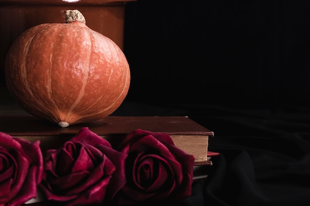Pumpkin and roses on black background