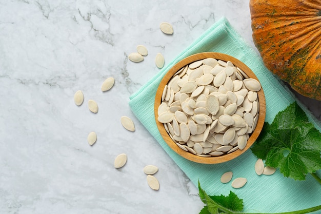 Free photo pumpkin seed put in wooden bowl on white marble floor