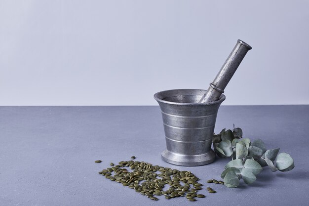 Free photo pumpkin seeds on the blue ground with a metallic blender around.