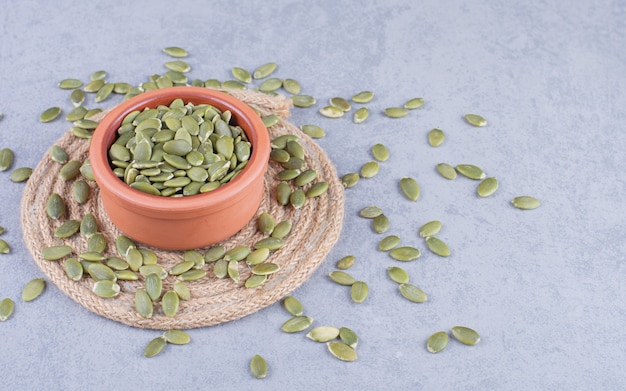 Pumpkin seeds in a bowl on the trivet, on the marble.