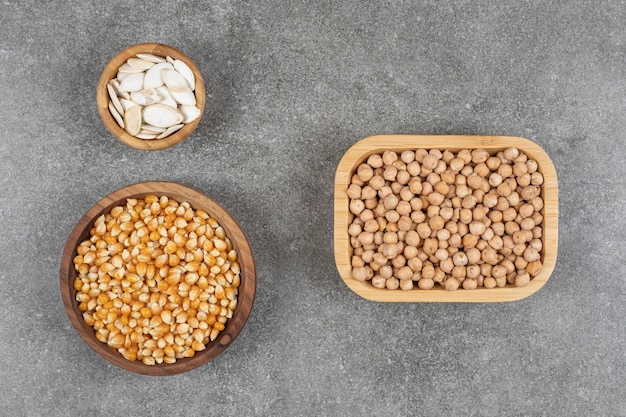 Pumpkin seeds, corn kernels and peas wooden bowls.