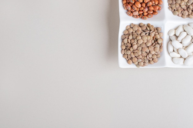 Pumpkin seeds with lentils and beans in white cups.