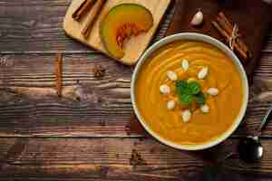 Foto gratuita zuppa di zucca in una ciotola bianca posta sul pavimento di legno