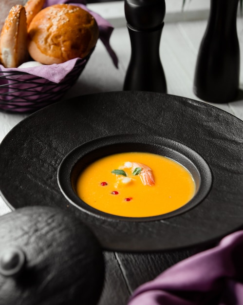 Zuppa di zucca con gamberi e un cesto di pane