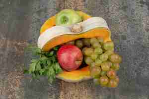 Foto gratuita zucca con mele e uva sulla superficie in marmo.